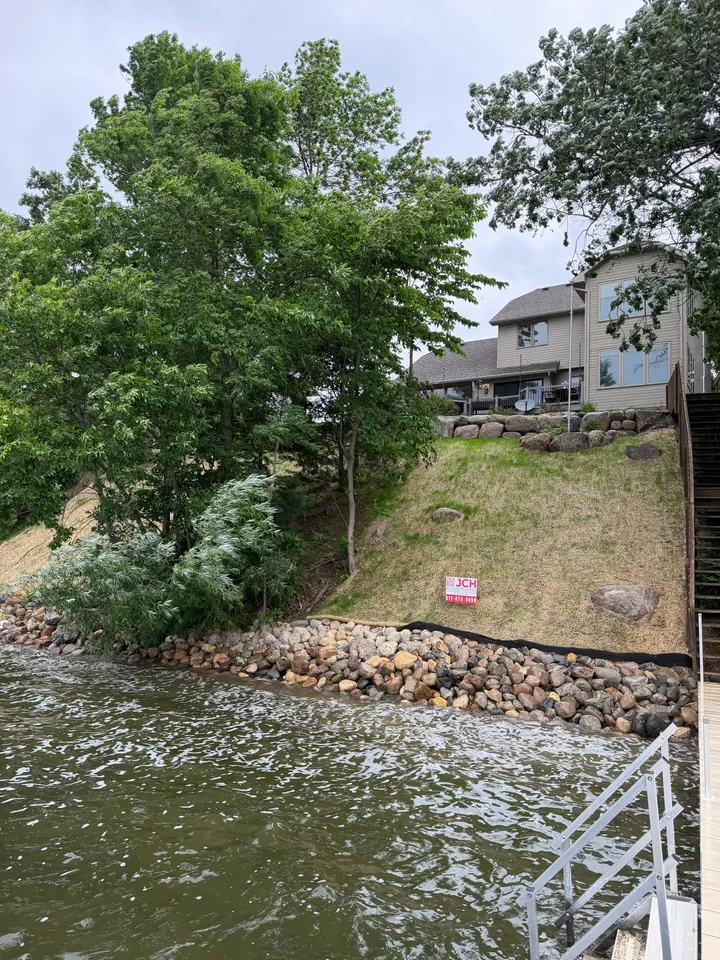 Riprap shoreline at the base of a seeded lake bank with a stairway down to a dock